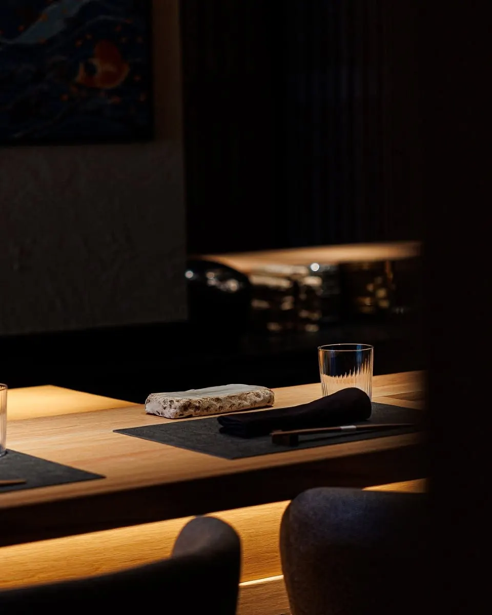 A place setting at the counter: chopsticks, a stone plate and a glass
