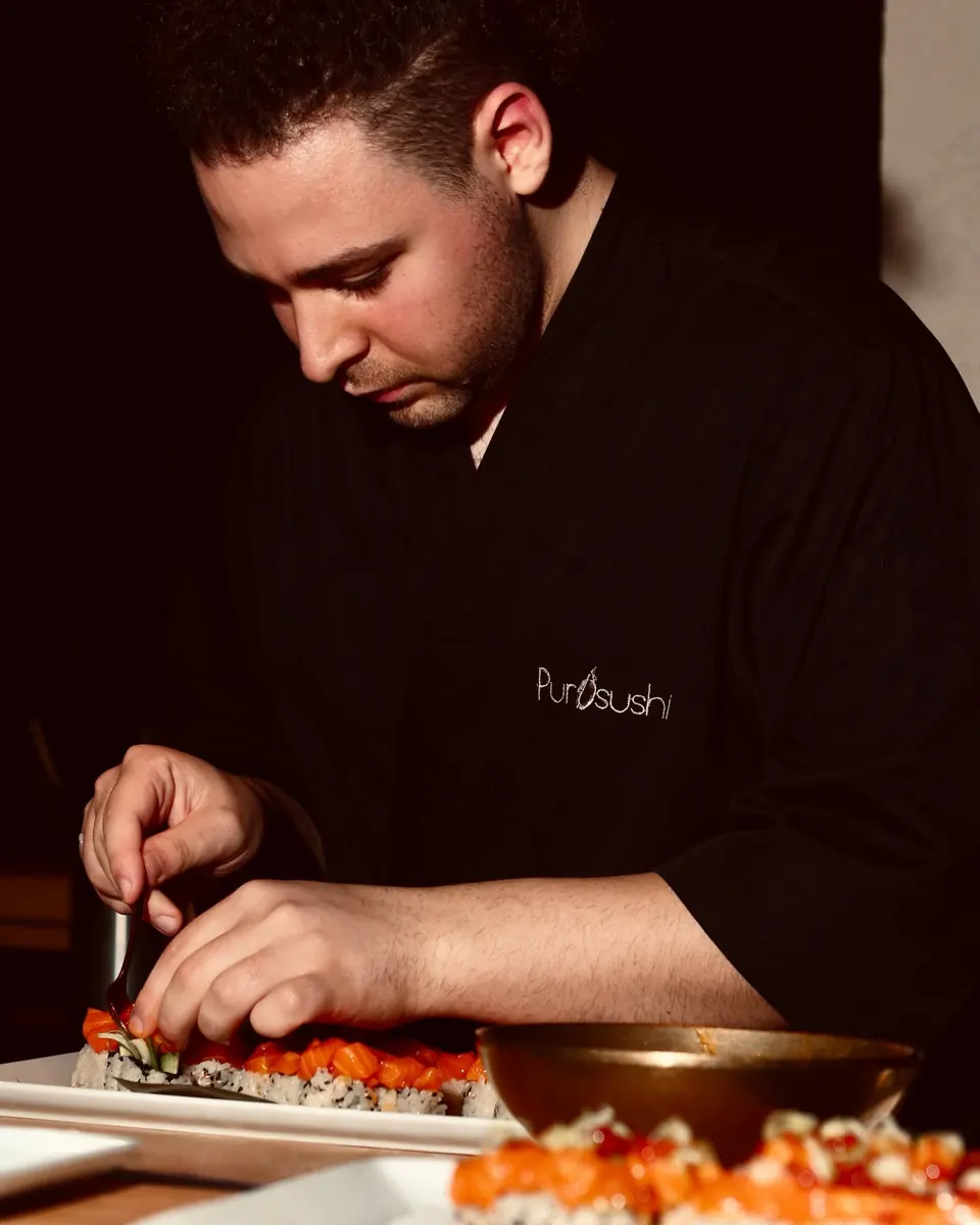 A PurOsushi chef finishing a futomaki roll