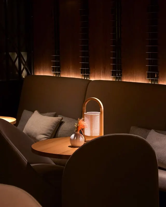 A corner sofa with cushions and a table lamp in the Lounge